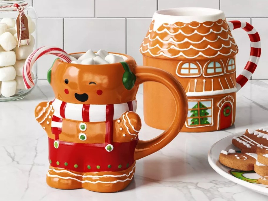 gingerbread man and gingerbread house shaped coffee mugs on a kitchen counter