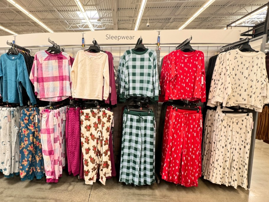 women's plush pajama tops and pants in plaids and Christmas patterns on a store display wall at Walmart