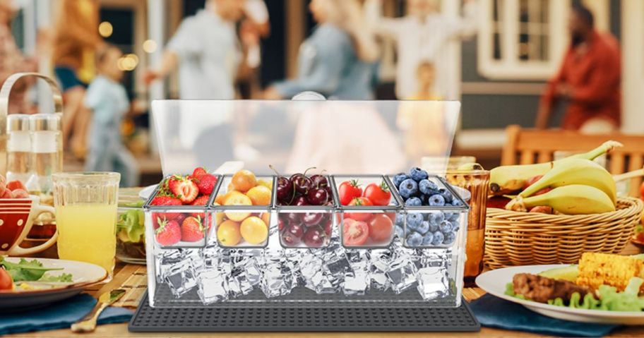 A Honeyeras Condiment Server filled with fruits on a table at a party