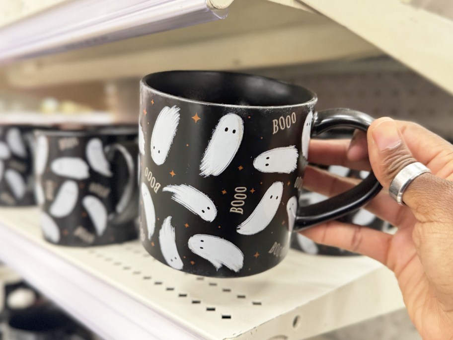hand holding up black coffee mug with ghost print