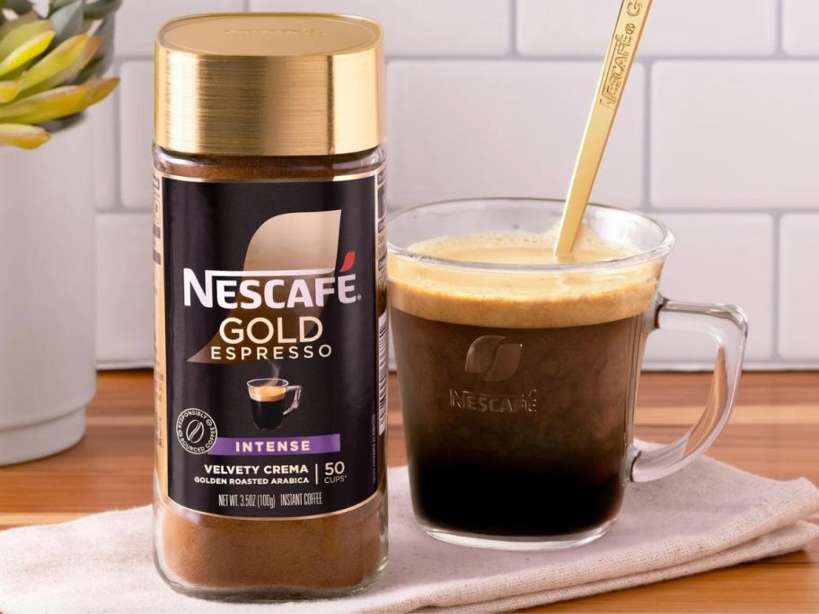 A bottle of Nescaffe Gold Espresso next to a cup with a spoon in it