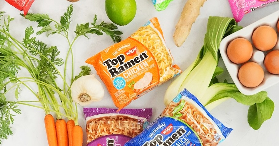 multiple packs of Nissin Top Ramen surrounded by veggies and eggs