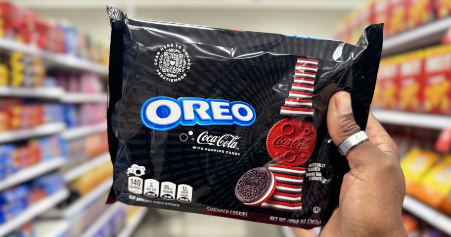 hand holding up a black package of OREO Coca-Cola Cookies