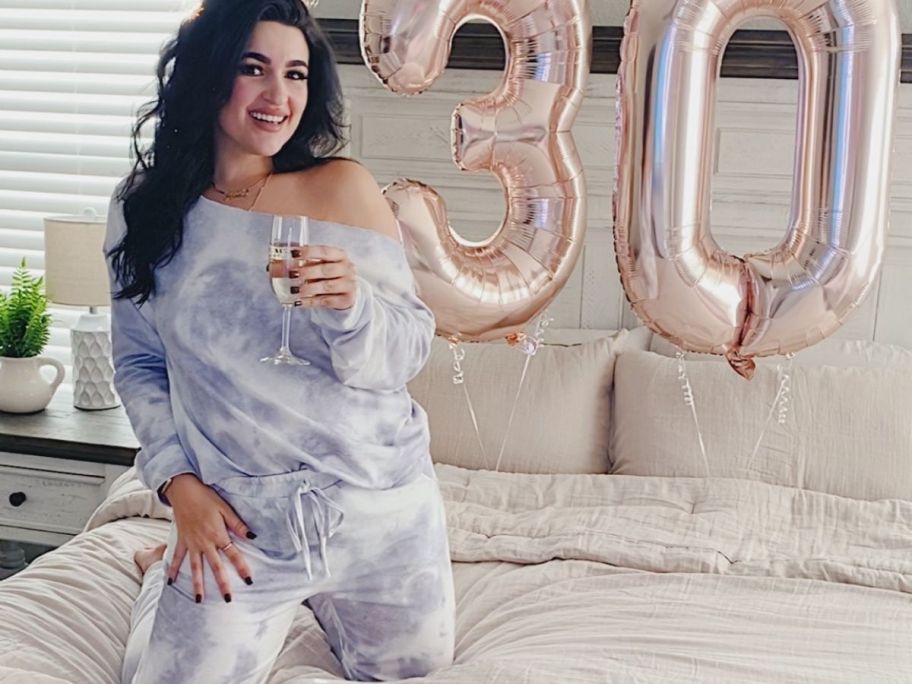 Woman on a bed holding a glass of champagne next to a balloon shaped like the number 30 while wearing a PrettyGarden 2-piece Lounge Set