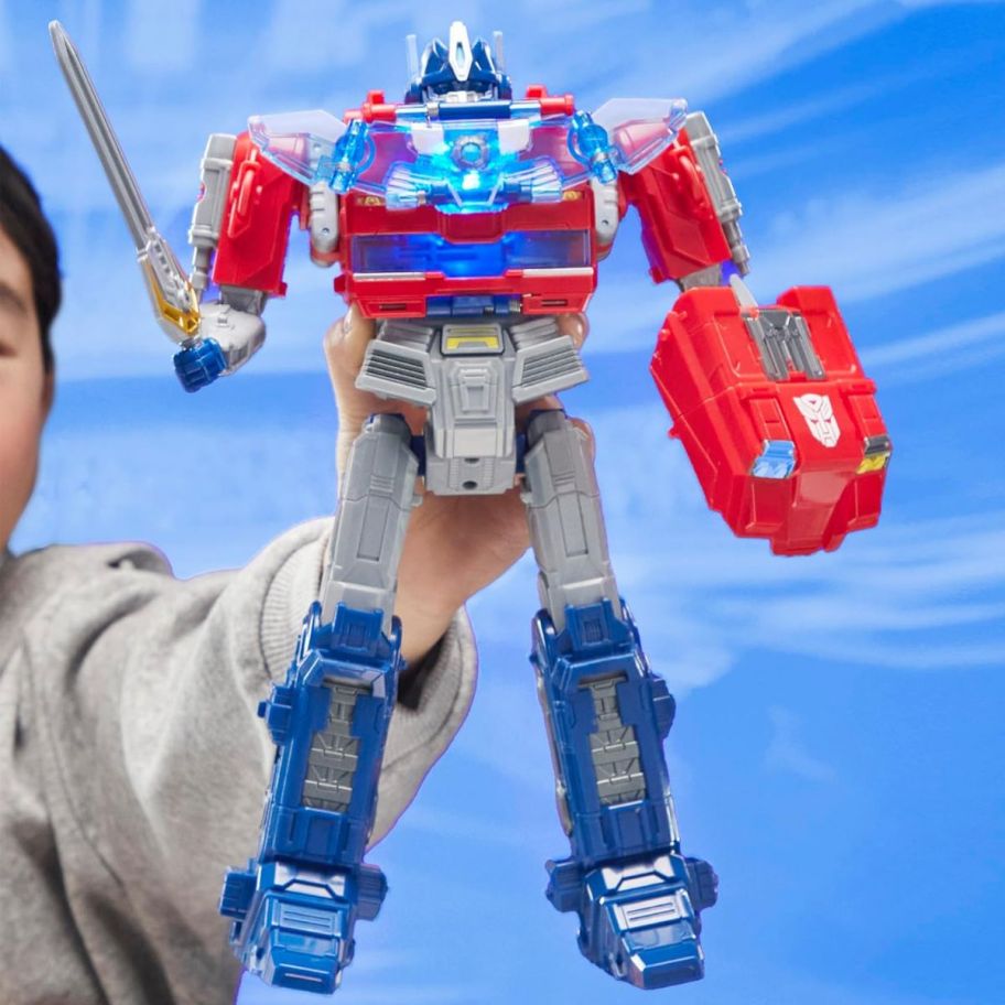 a little boy holding a power flip optimus prime action figure