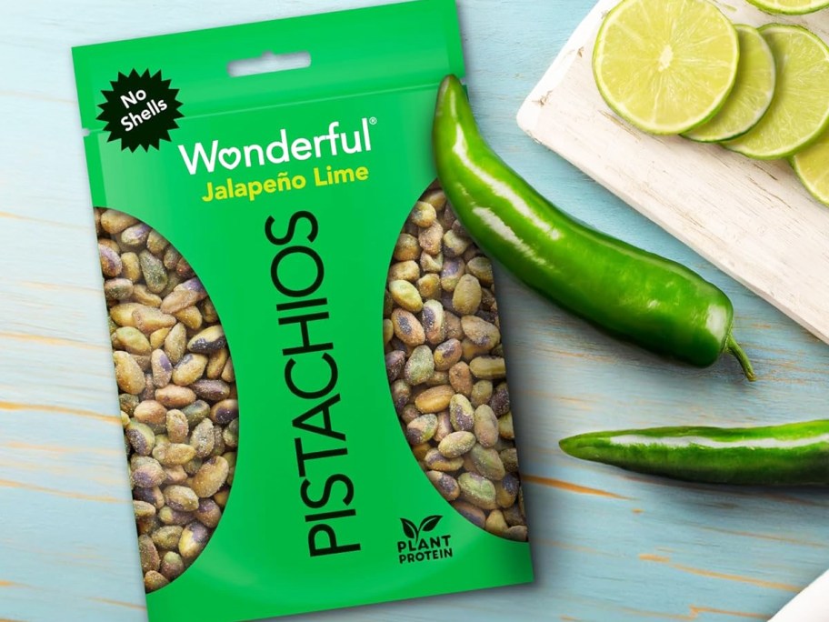 green bag of Wonderful Pistachios No Shells Jalapeño Lime near jalapeños and limes