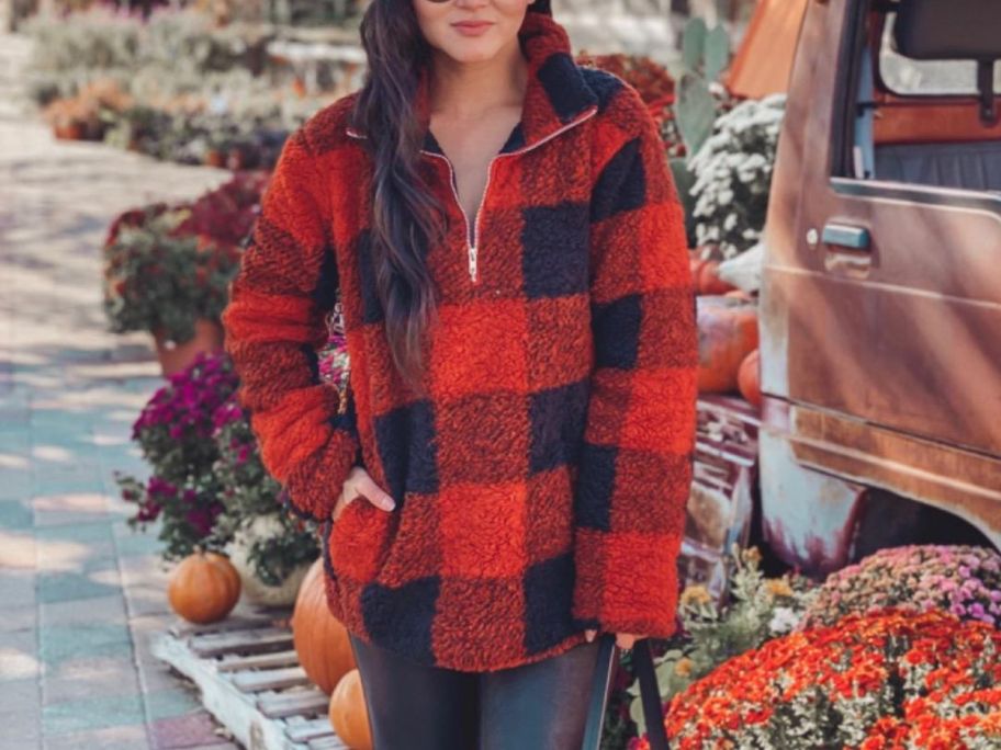 A woman enjoying a fall festival scene while wearing a red and black plaid jacket