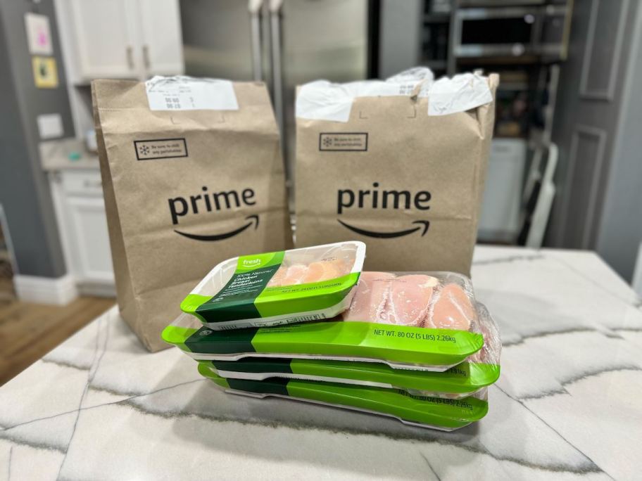 stack of packs of chicken on countertop with amazon prime brown bags