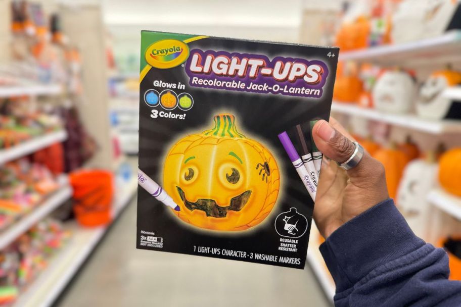 a womans hand displaying a crayola ight-ups jack o lantern