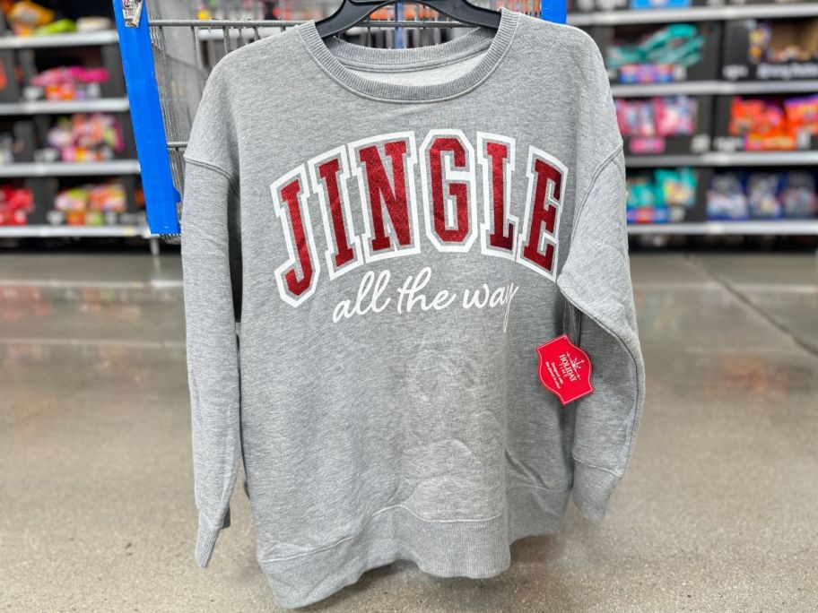 jingle all the way sweatshirt hanging on the side of a walmart shopping cart