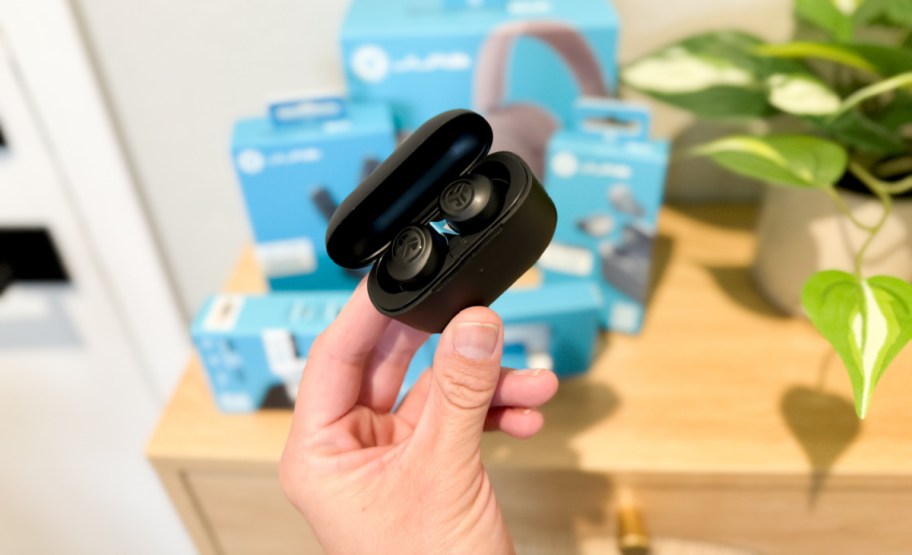 jlabs go air earbuds in case being held by a hand in front of other jlab items