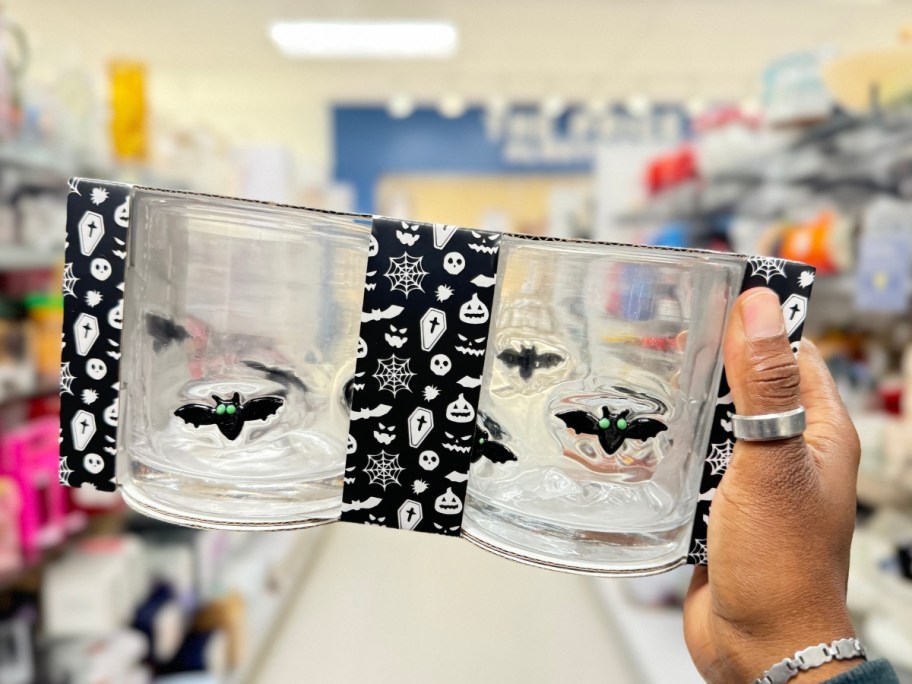 hand holding a set of clear glass mugs with bats on them