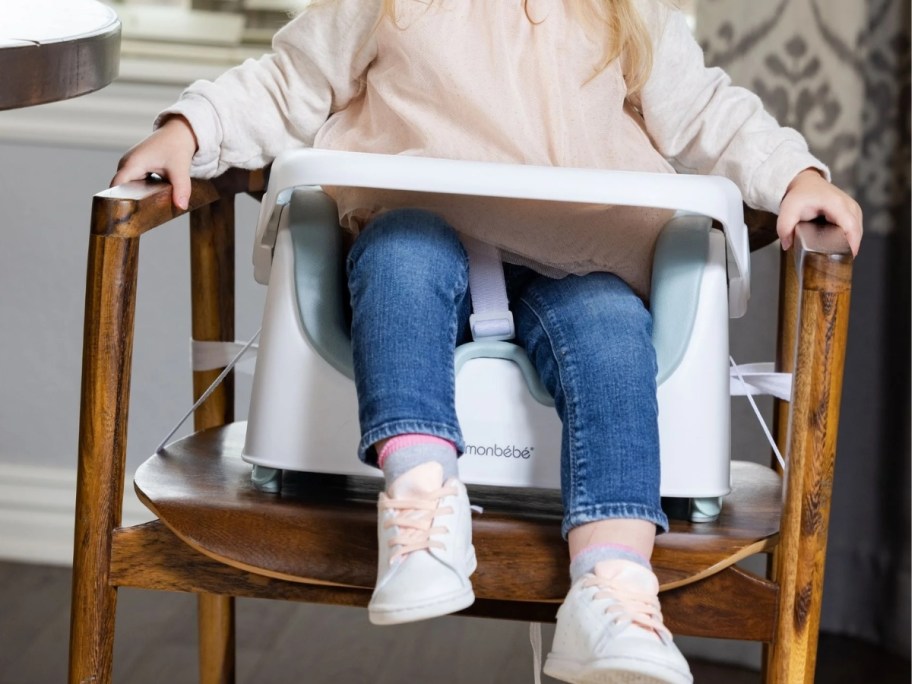 toddler sitting in a chair in a booster seat with a tray