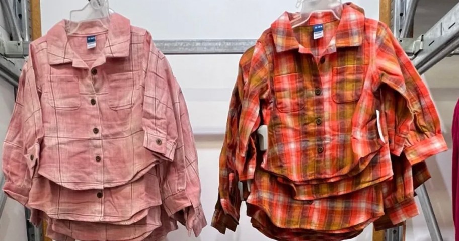 pink and red flannel shirts hanging in store