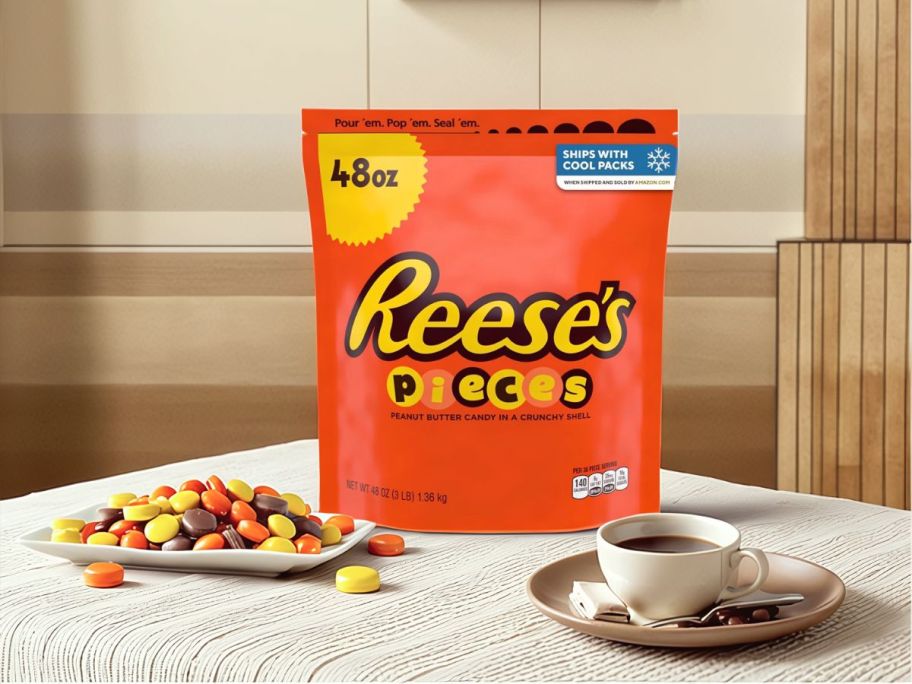 large bag of Reeses pieces on table with some on plate next to bag and coffee
