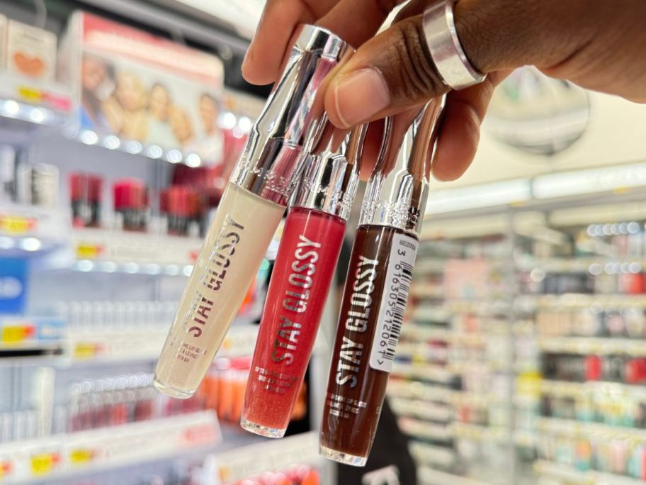 hand holding 3 rimmel Stay Glossy Lip Glosses in store