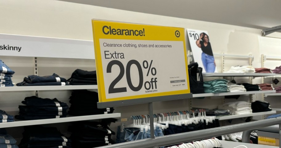 a yellow and white sign that says "Clearance Extra 20% off ticketed items" on a clothing rack in Target