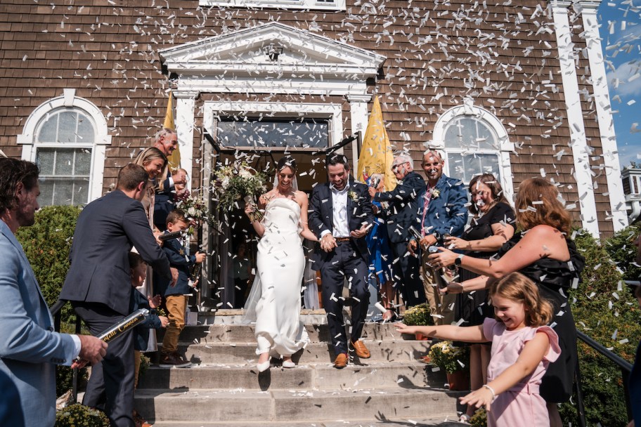 Married couple walking out of church with flying confetti