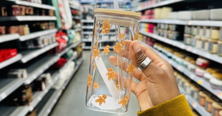 hand holding a square glass tumbler with Gingerbread men on it and a bamboo lid and glass straw