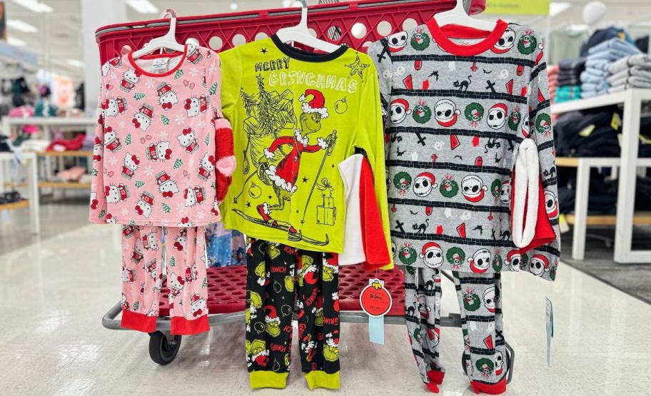 three sets of kids pajamas hanging on the side of a target cart 