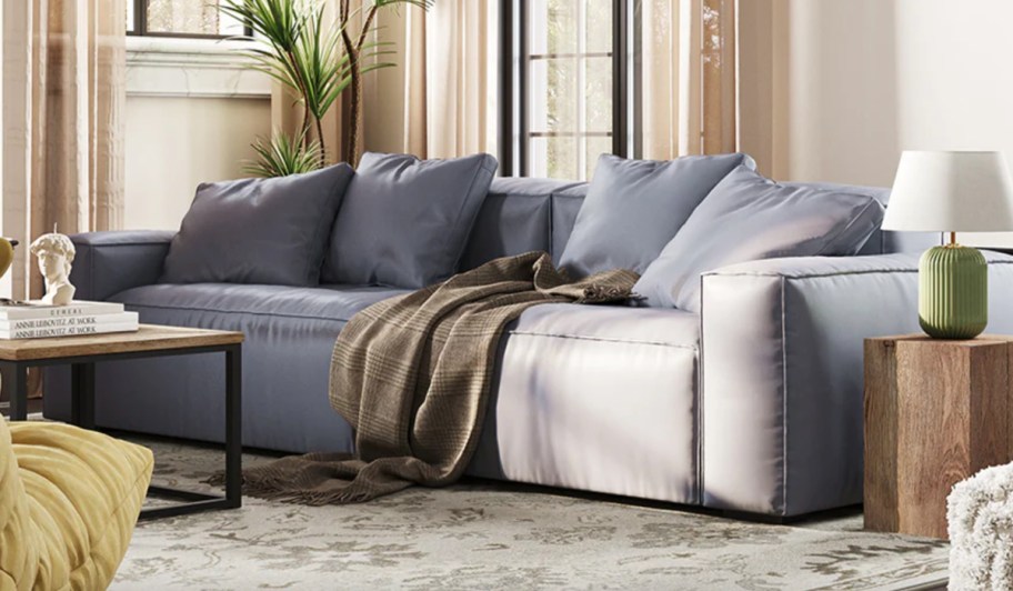 grey 4 seater couch with blankets on it