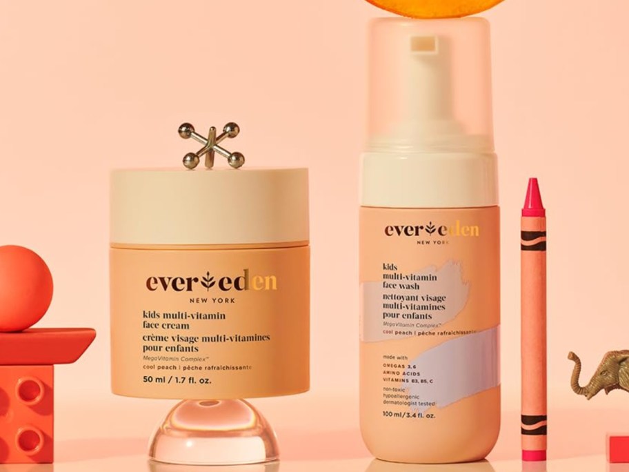 peach and cream color Evereden Kids Happy Face moisturizer and face wash surrounded by kids toys and a crayon