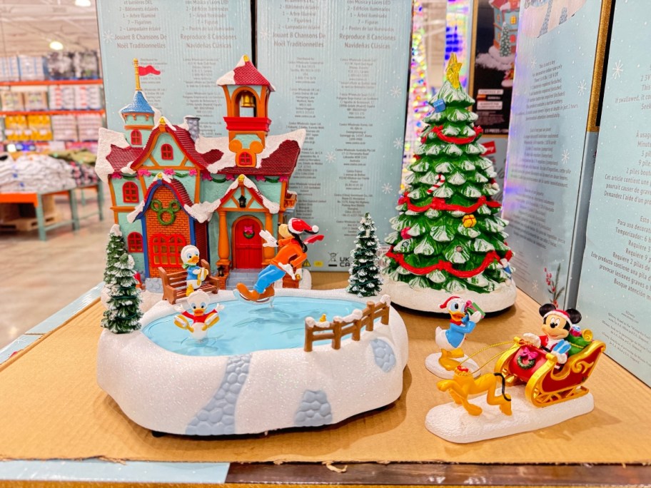 a Disney Holiday village piece set with an ice skating pond, holiday decorated house, Christmas tree and Disney figures