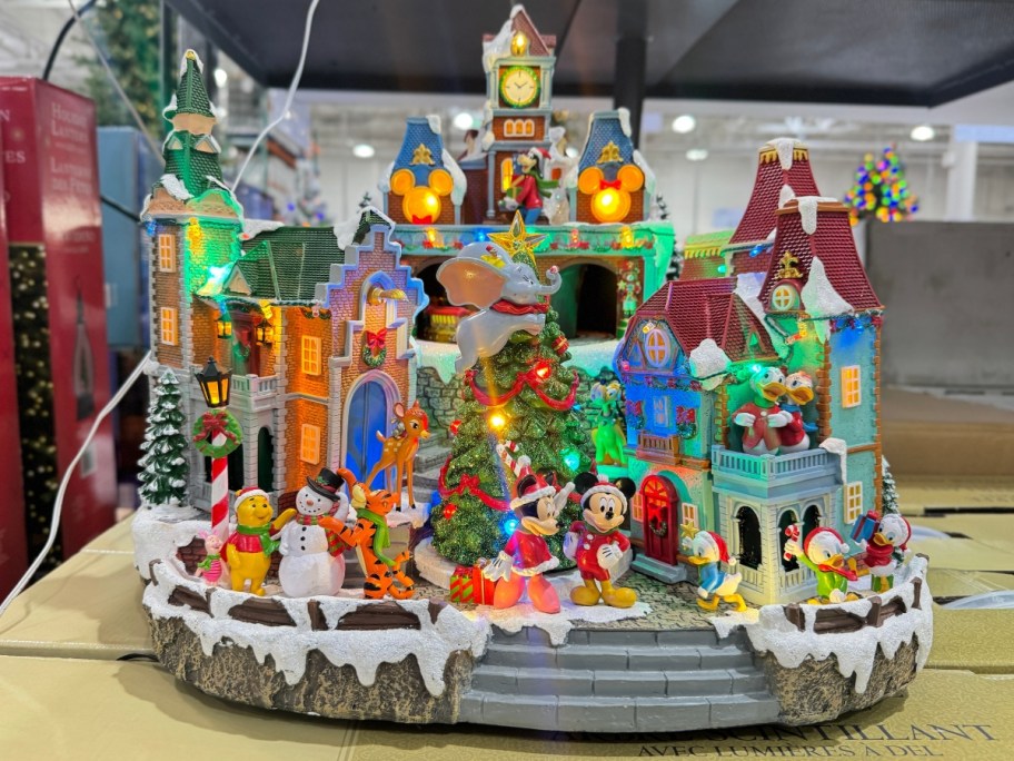 a large Disney Christmas village piece with houses, snow, various Disney figures and Christmas themed items on a shelf at Costco