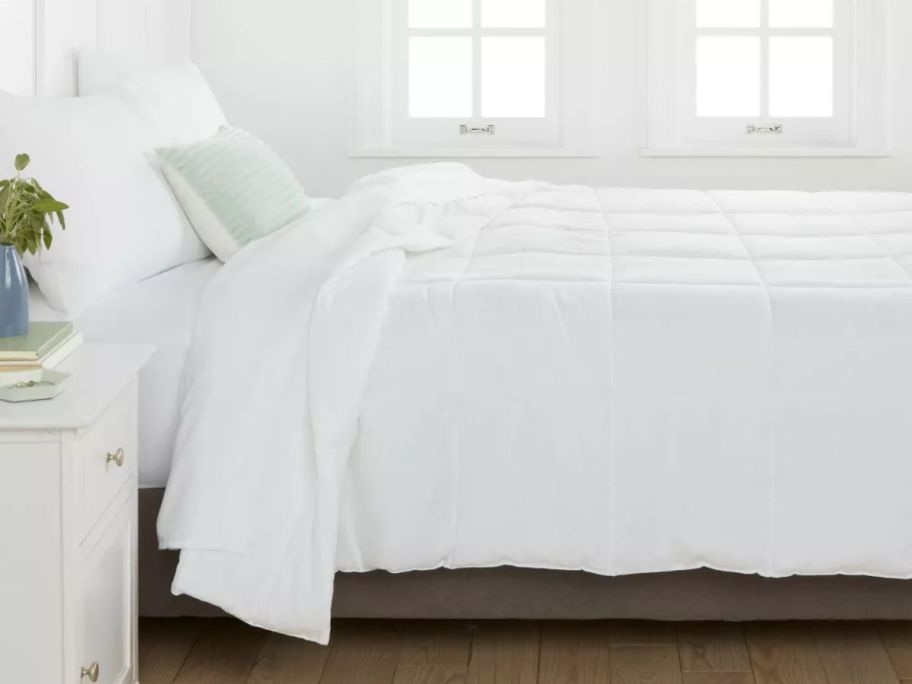 white comforter on a bed with white sheets and pillows