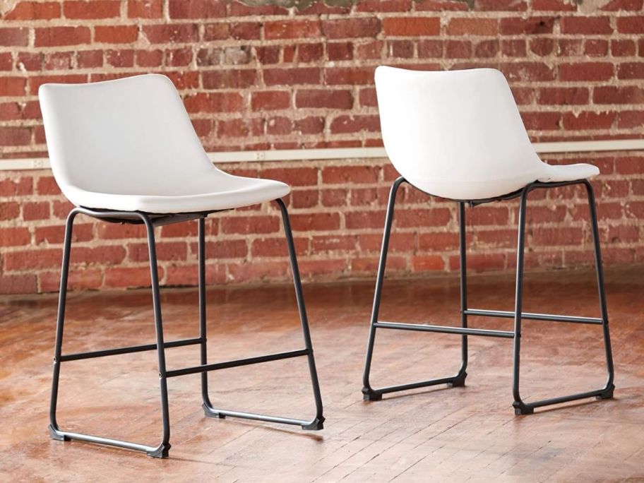 two white counter height bar stools in a room with a hardwood floor