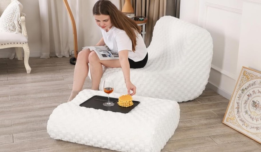 Woman sitting in a bean bag chair with a foot stool.