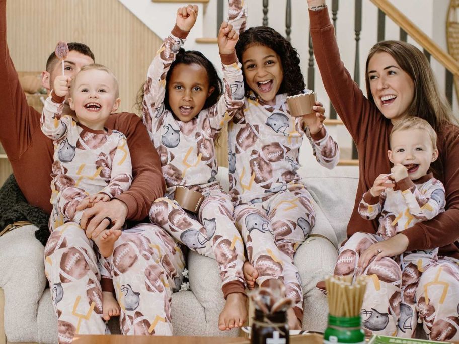 family wearing Burt's Bees Baby Football Season Organic Matching Family Pajamas on couch