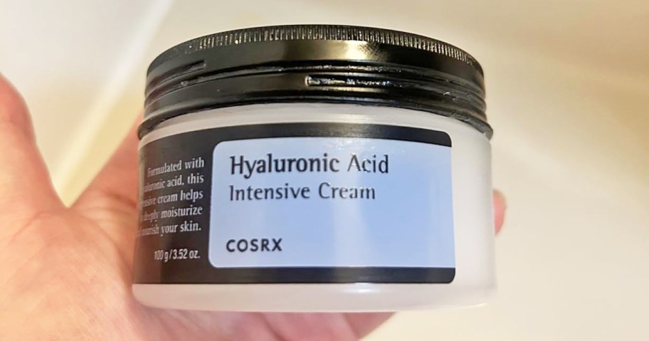 hand holding a container of COSRX Hyaluronic Acid Moisturizing Cream