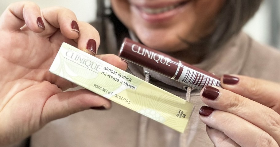 woman holding up box and tube of Clinique Black Honey Almost Lipstick