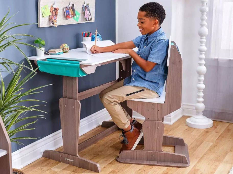 Boy sitting at a KidKraft Grow Together Pocket Adjustable Wooden Desk & Chair