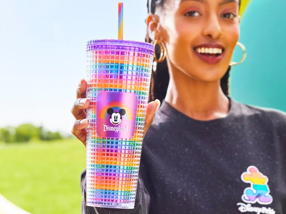 woman holding up a rainbow disney tumbler