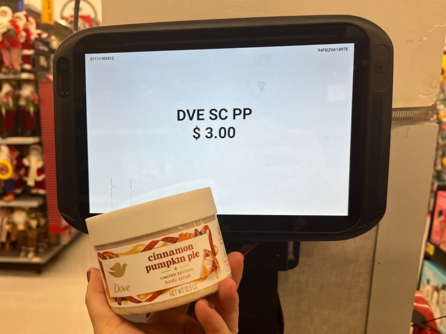 Dove Exfoliating Body Scrub in Cinnamon Pumpkin Pie in hand in hand in store being held in front of price check scanner