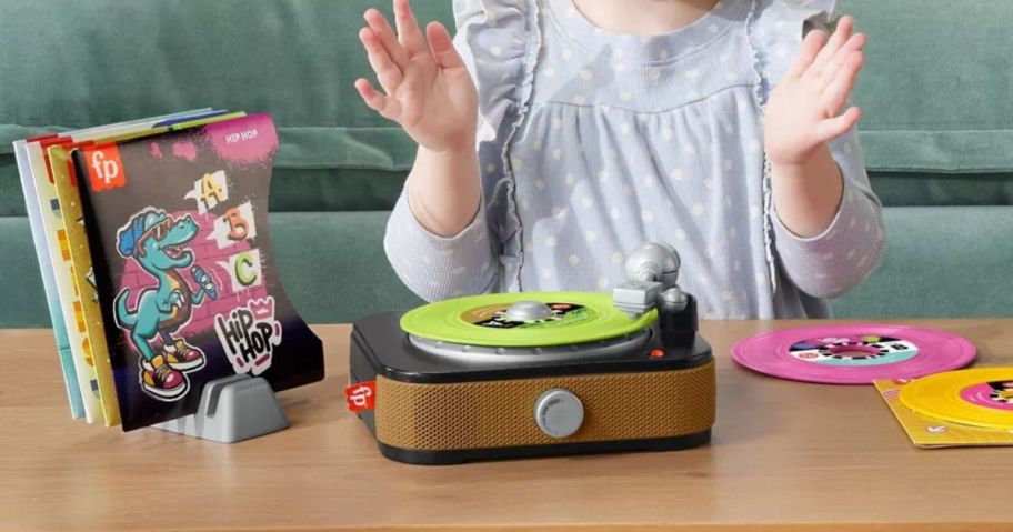 girl sitting in front of Fisher-Price Rockin' Record Player Musical Toy on table