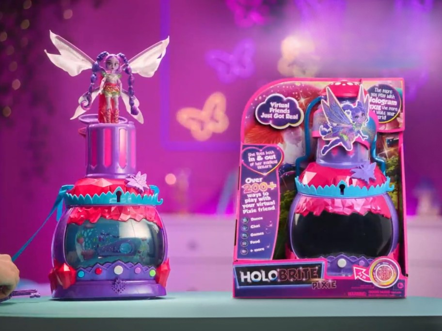 a HOLOBRITE Pixie Lantern toy next to the box it comes in, pink on a purple background