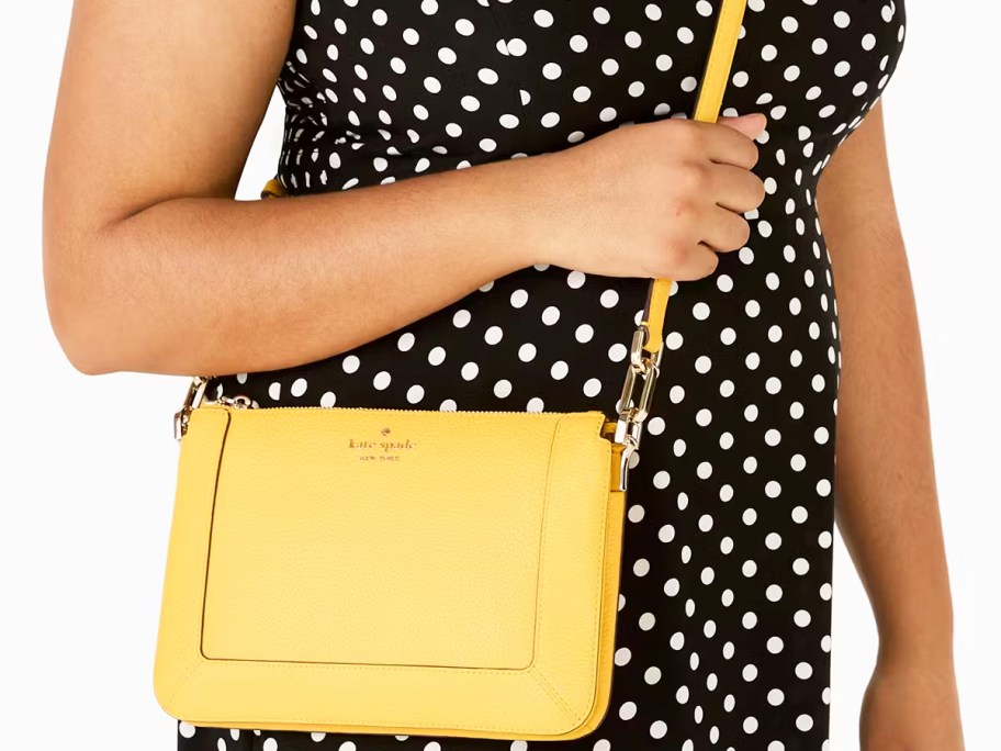 woman in a black and white polka dot dress with a yellow crossbody bag