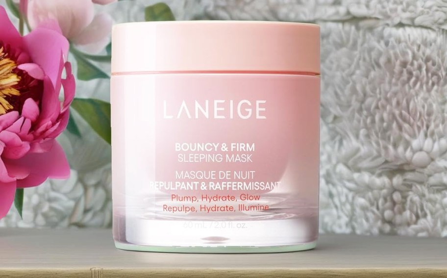 pink jar of Laneige Bouncy & Firm Sleeping Mask near pink flowers