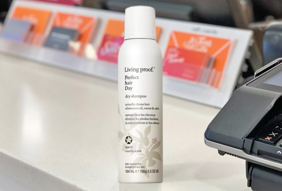 white bottle of Living Proof Perfect Hair Day Dry Shampoo on store counter