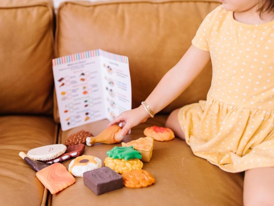 kid playing with Melissa & Doug Food Fun Combine & Dine Dinners on couch