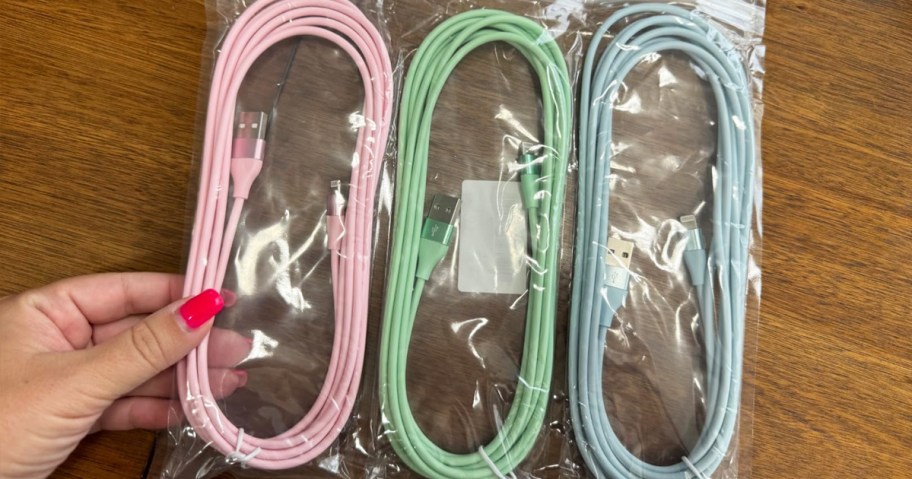 hand holding three pastel iphone charging cables in bag