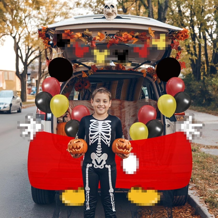 child next to a Mickey Mouse Trunk or Treat display