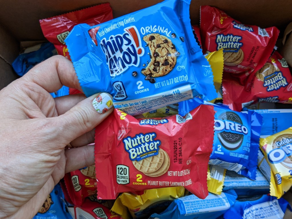 woman holding up snack packs of Chips Ahoy and Nutter Butters