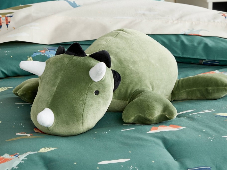 Pillowfort Dinosaur Weighted Plush Kids' Throw Pillow on the bed