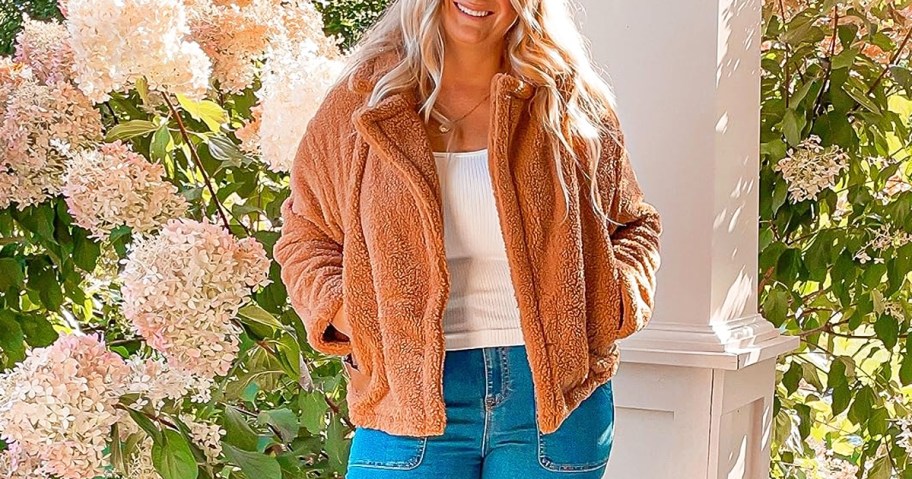 woman wearing jeans, white top, and brown sherpa jacket