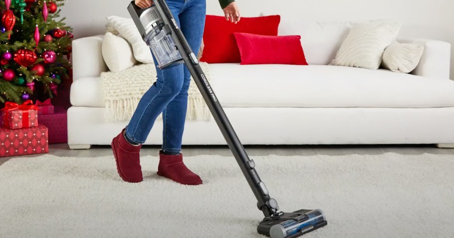 woman using a shark cordless vacuum on rug