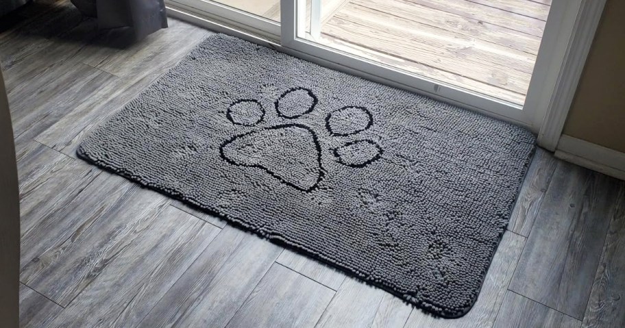 grey doormat with large black paw print in front of glass door